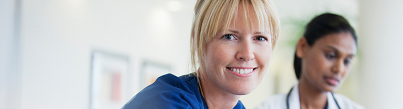 Nurse smiling with doctor in the background